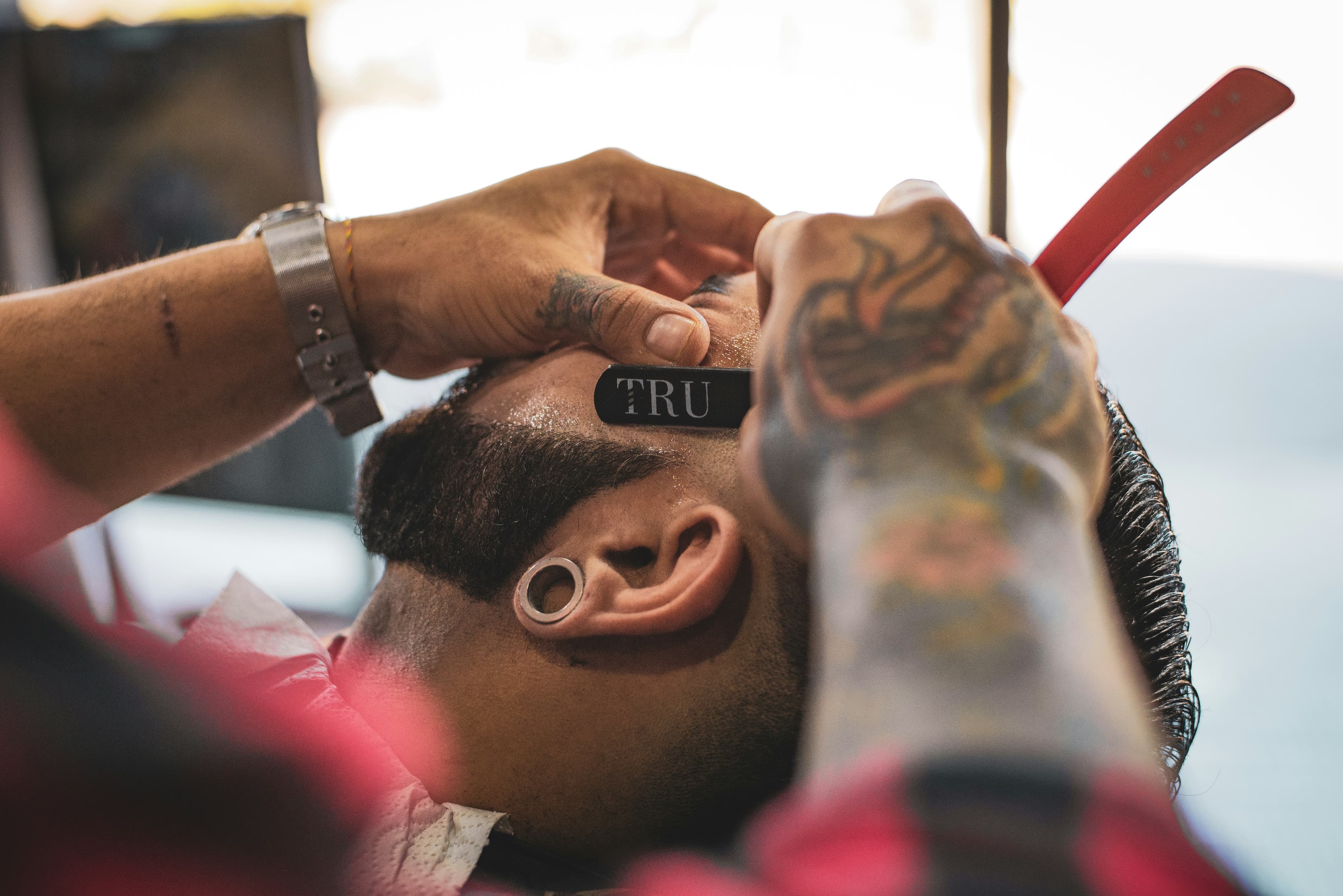 Barber using straight razor to shave client's beard